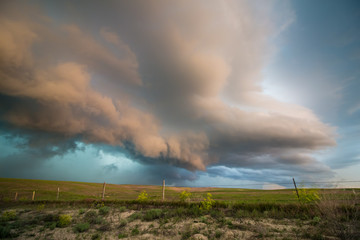 The shelf cloud of a severe storm is lit beautifully by light from the setting sun in this dramatic...