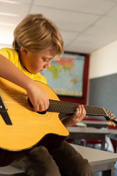 Boy playing guitar in a classroom