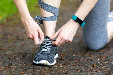Young woman makes fitness and ties shoelaces