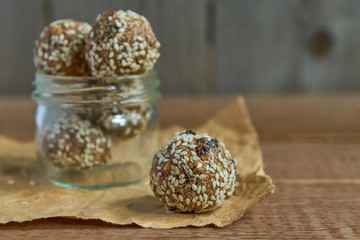 Tasty vegan raw protein truffles or energy balls with prunes, seeds and nuts in a jar on wooden background
