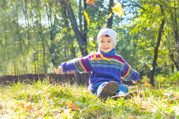 boy in sweater and hat sitting on the grass