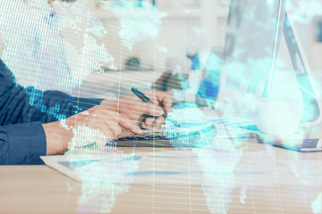 Fototapeta premium Double exposure of businessman working on laptop on background. International business hologram in front. Concept of success.