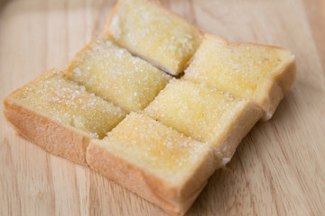 Toasted bread with butter and sugar in wooden tray with table background