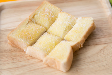Toasted bread with butter and sugar in wooden tray with table background