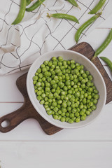 A bowl of fresh green peas on the white table
