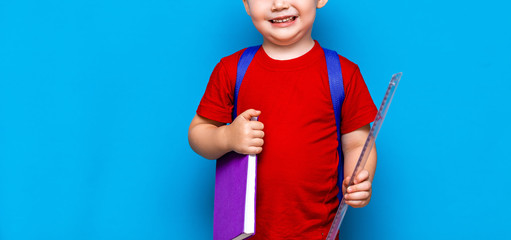 small happy smiling boy with glasses on his head, book in hands, schoolbag on his shoulders. back to school. ready to school