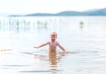 small boy with blonde hair have fun in sea swimming, summertime, hardening