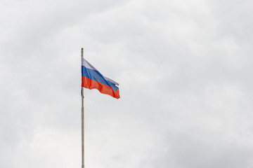 Waving flag of Russia against gloomy cloudy sky