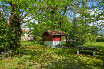 Fototapeta na wymiar Garden, little red house and stone table in a sunny summer day, Italy