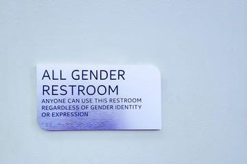 "All Gender Restroom" silver sign on a blue wall