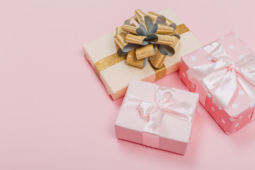 Gift box wrapped in pastel  paper with pink ribbon on pink surface. Top view  with copy space.