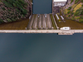 Aerial top down view at a dam of hydro electrical station. The dam is a border line that holds blue waters of Detroit Lake.