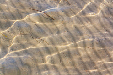 Close-up shot of breathtaking natural texture of the sea bottom with sand and stripes made by waves.