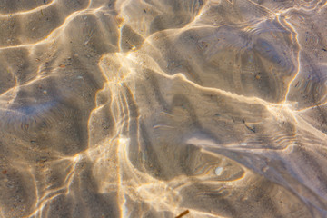 Fototapeta na wymiar Close-up shot of breathtaking natural texture of the sea bottom with sand and stripes made by waves.