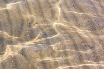 Close-up shot of breathtaking natural texture of the sea bottom with sand and stripes made by waves.