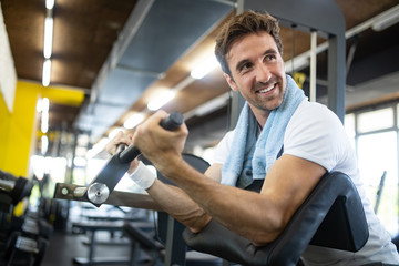 Fototapeta na wymiar Young fit handsome man doing exercises in gym