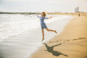 Beautiful girl in blue dress is walking on the beach. Amazing summer photo. Woman dancing and...