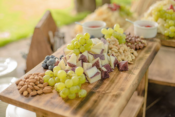 Food, sliced goat cheese with sprigs of grapes and blueberries, and cashew and almond nuts