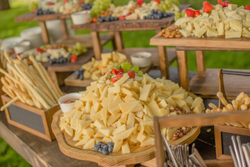 A large number of slices of sliced cheese with nuts and berries, snacks at a party