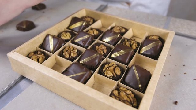 Baker's hands put handmade chocolate candies in a beautiful box