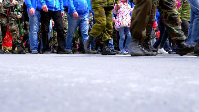 Legs of people walking and standing in line outside.