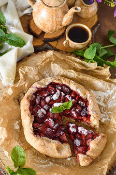 Strawberry galetta with mint leaves with a cut piece of coffee and flowers in a rustic style top view