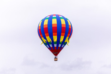 Fototapeta na wymiar Woodburn, Oregon \ USA - 21 April 2019: A hot air balloon with blue, yellow and red stripes taking passengers into the sky