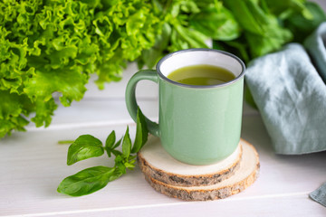 Freshly blended green smoothie in a ceramic cup on the table. Detox vegetable juice. Healthy...
