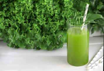 Freshly blended green smoothie in in a glass with straws on the table. Detox vegetable juice. Healthy lifestyle concept. Raw drink for vegan diet.