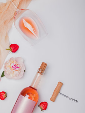 Creative summer flat lay with rose wine, delicious strawberries and beautiful peonies