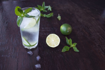 Mojito cocktail on a dark wooden background. Fresh lime juice with mint and ice. Cooling drink