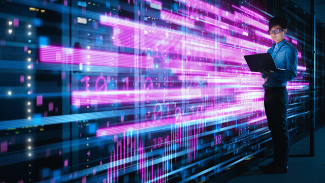 Shot of Asian IT Specialist Using Laptop in Data Center Full of Rack Servers. Concept of High Speed Internet with Pink Neon Visualization Projection of Binary Data Transfer