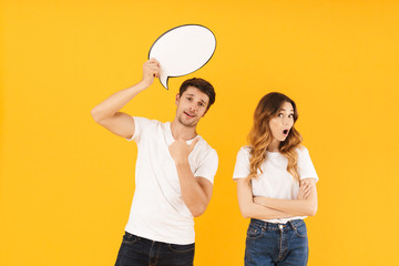 Portrait of excited couple man and woman standing together while holding blank thought bubble