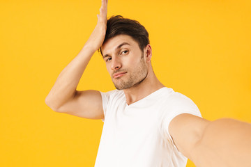 Photo of brunette man in basic t-shirt posing at camera with arrogant look while taking selfie photo