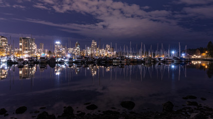 Fototapeta na wymiar Vancouver, BC \ Canada - 13 March 2019: A night long exposure photo of marina inside Burrard Inlet of Vancouver Harbor with many yachts and boats against colorful illuminated city skyline