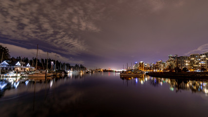 Vancouver, BC \ Canada - 13 March 2019: A night long exposure photo of yachts and boats  in marina of Burrard Inlet of Vancouver Harbor. City skyline and Canada place lights are in the background