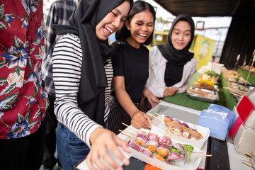 group of young women at a street food restaurant are choosing food