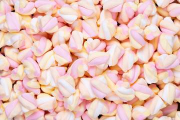 Fototapeta premium Marshmallows on blue background with copyspace. Flat lay or top view. Background or texture of colorful mini marshmallows.