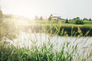 Quiet river, green grassy shore and russian village countryside background