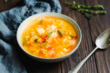 Spring vegetable soup with chicken stock for one person on wooden table.  Rustic style, close-up view.