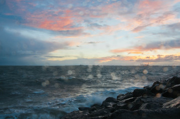 Dramatic splashing ocean wave in the evening with twilight sky in Winter at breakwater at St Kilda...