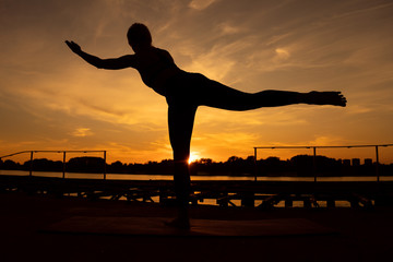 Woman practicing yoga in sunset. Virabhadrasana / Warrior 3 pose