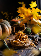 tasty homemade pumpkin orange waffles on wooden board on brown rustic table with pumpkins