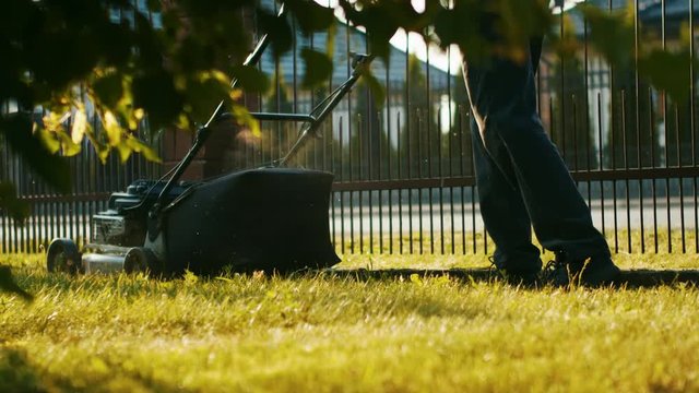 Man cutting grass with a full bag lawn mower in the backyard