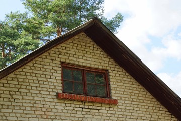 old brown brick attic with a small window against the sky