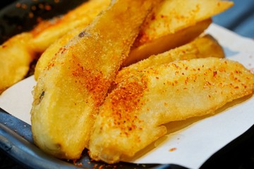 Selective focus of french fries with cayenne pepper on black plate, ready to eat or serve, Soft focus