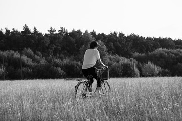 Fototapeta premium Happy girl rides a classic bike among beautiful nature.