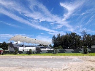 Blurred image of exterior view of the public swimming pool with blue sky and parking, Copy space