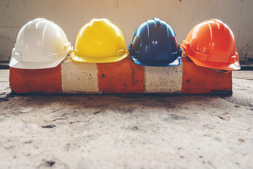 Safety helmet, white, yellow, blue and orange, placed on the cement floor in the construction site.