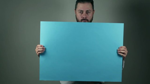 Casual beard man in shirt holding a blue cartboard to write something on it. News and business concept